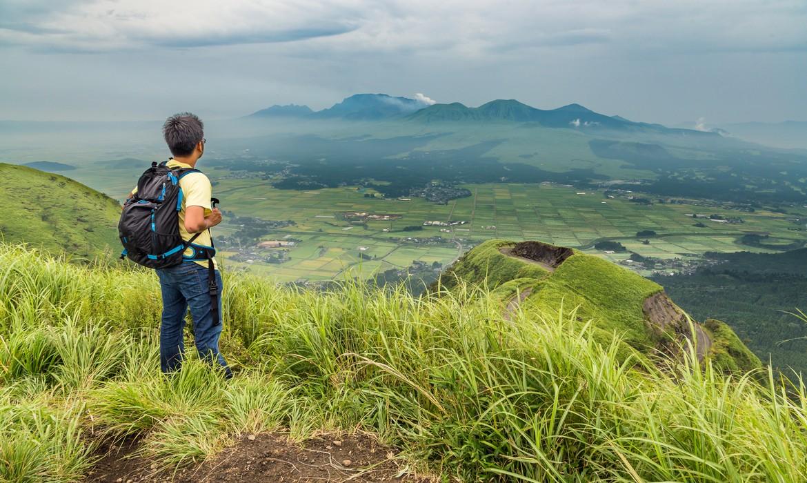 Hiker trekking to the hill top and watching mount Aso volcano